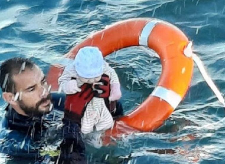 Un submarinista de la Guardia Civil, con un bebé cuya familia se había echado al agua en Ceuta, este lunes