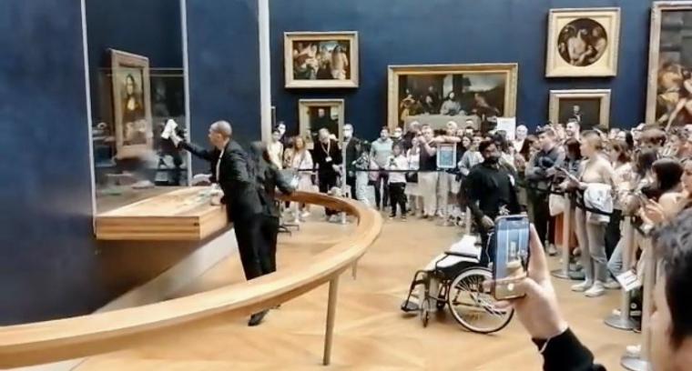  Un hombre en silla de ruedas y ataviado con peluca le lanza una tarta a la Mona Lisa 
